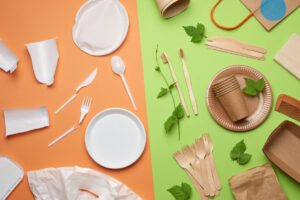 non-degradable plastic waste from disposable tableware and a set of dishes from environmental recycled materials on a green background